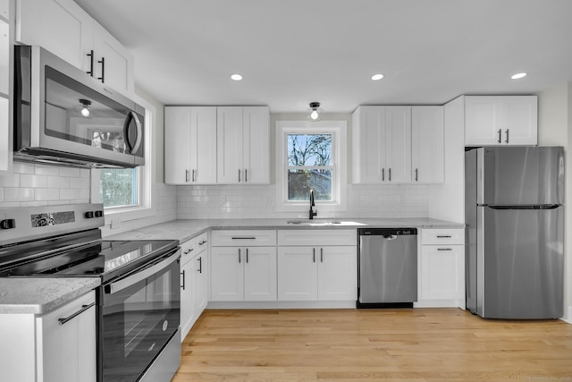 kitchen featuring white cabinets, appliances with stainless steel finishes, sink, and light hardwood / wood-style flooring