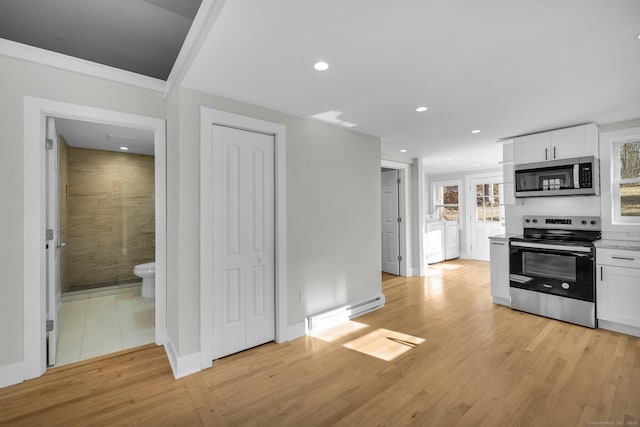 kitchen with light wood-type flooring, stainless steel appliances, backsplash, and white cabinetry