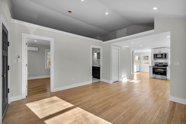 unfurnished living room with vaulted ceiling, a wall mounted air conditioner, and light hardwood / wood-style floors