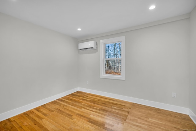 unfurnished room featuring hardwood / wood-style flooring and a wall mounted air conditioner