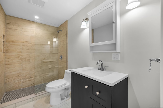 bathroom featuring toilet, vanity, tile patterned flooring, and tiled shower