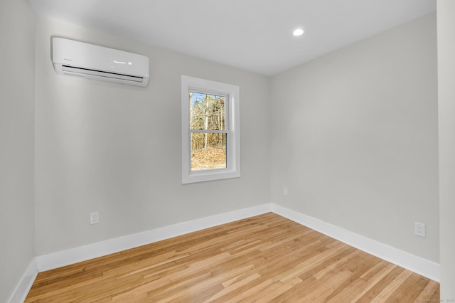 unfurnished room with a wall mounted AC and hardwood / wood-style floors