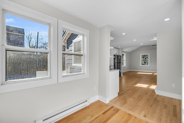 hallway featuring baseboard heating, lofted ceiling, plenty of natural light, and light wood-type flooring