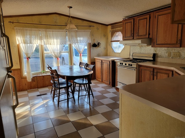 kitchen with a textured ceiling, hanging light fixtures, white gas range oven, and vaulted ceiling