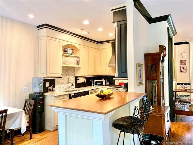 kitchen featuring white cabinets, light hardwood / wood-style floors, sink, a breakfast bar, and crown molding