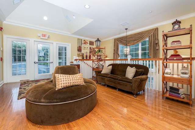 living room featuring light hardwood / wood-style flooring, crown molding, a notable chandelier, and vaulted ceiling