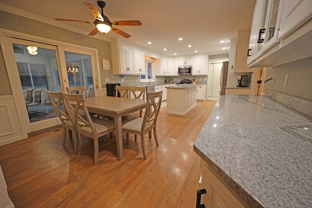 dining space with ceiling fan, ornamental molding, light hardwood / wood-style floors, and sink