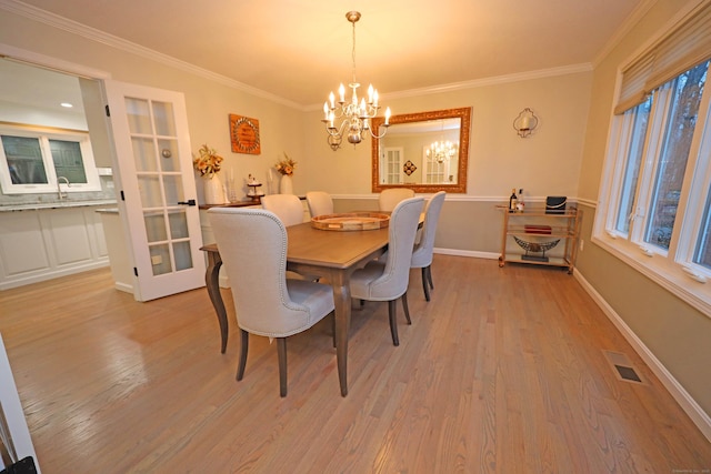 dining area featuring light wood-type flooring, a chandelier, and crown molding