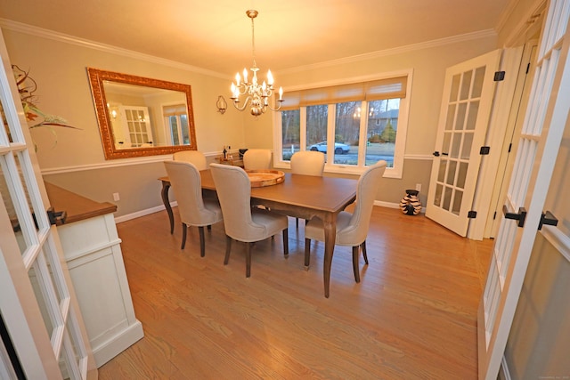 dining space with french doors, light hardwood / wood-style flooring, ornamental molding, and a notable chandelier