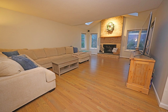 living room with a brick fireplace, vaulted ceiling with skylight, and wood-type flooring