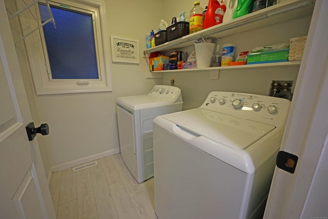 clothes washing area featuring light wood-type flooring and washer and clothes dryer