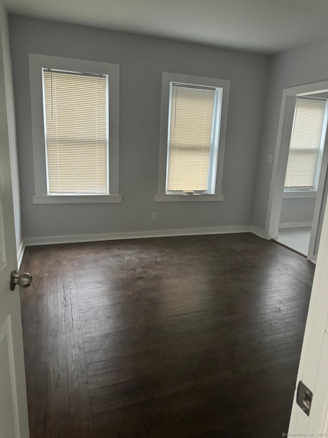 empty room with dark hardwood / wood-style floors and a wealth of natural light