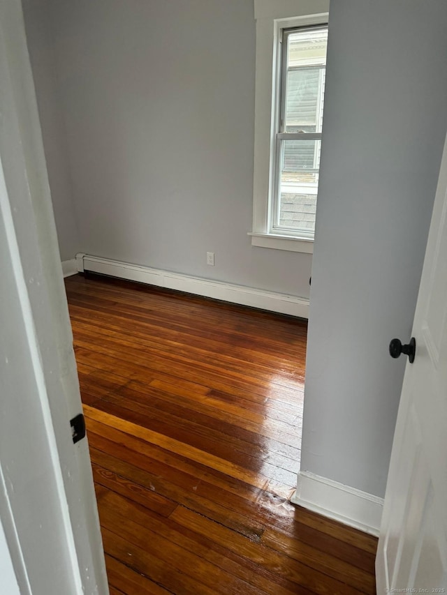 spare room with baseboard heating and dark wood-type flooring