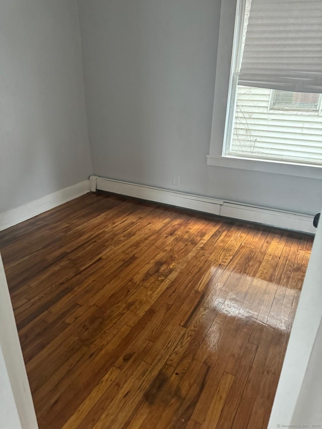 empty room featuring baseboard heating and dark hardwood / wood-style flooring