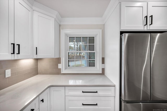 kitchen featuring stainless steel refrigerator, light stone counters, and white cabinetry