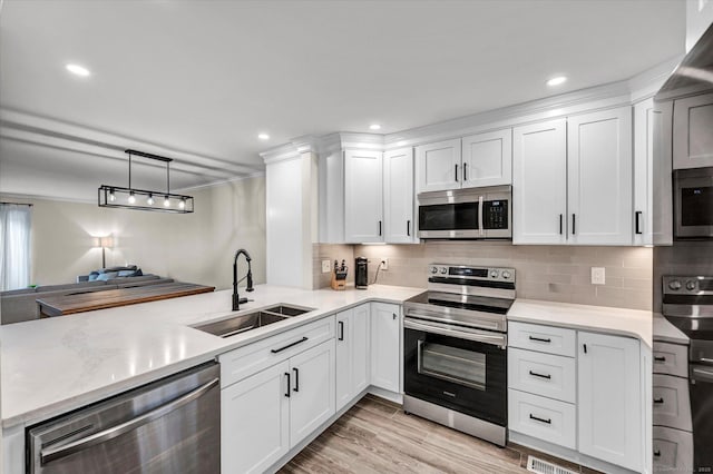 kitchen featuring sink, white cabinetry, appliances with stainless steel finishes, and hanging light fixtures