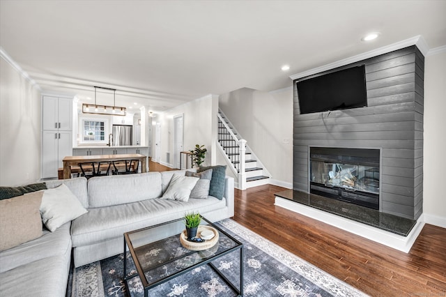 living room with crown molding, a fireplace, and hardwood / wood-style floors