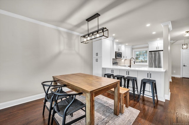 dining space featuring dark wood-type flooring, sink, and crown molding