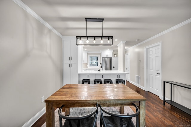 dining space featuring dark wood-type flooring, ornamental molding, and sink