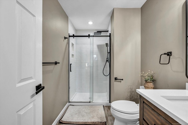 bathroom with toilet, vanity, wood-type flooring, and a shower with shower door