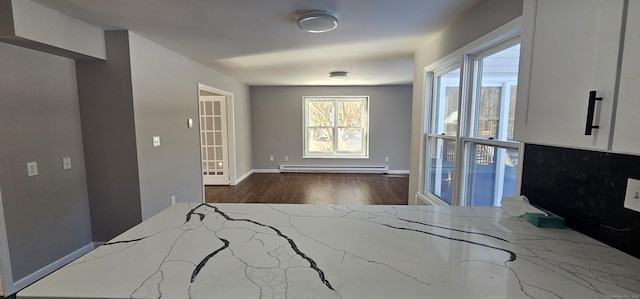 interior space featuring baseboard heating, light stone countertops, and dark hardwood / wood-style flooring