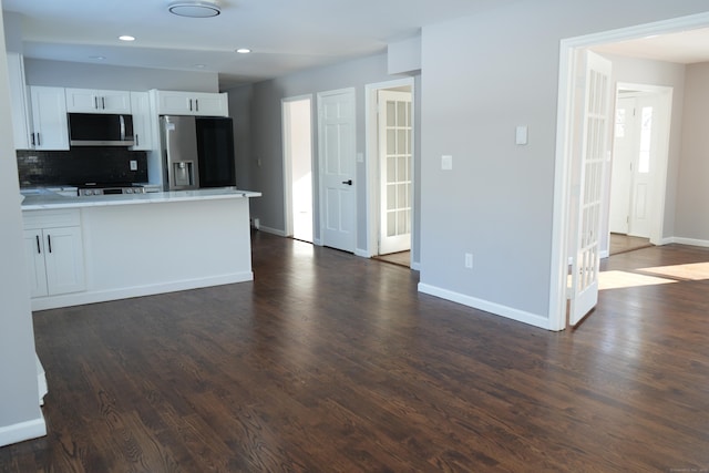 kitchen with decorative backsplash, white cabinets, appliances with stainless steel finishes, and dark hardwood / wood-style flooring