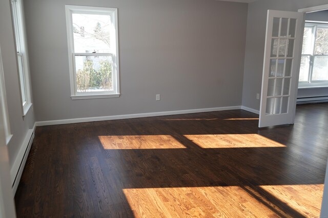 spare room with dark hardwood / wood-style floors, a healthy amount of sunlight, and baseboard heating