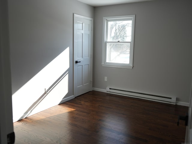 empty room with dark hardwood / wood-style floors and baseboard heating