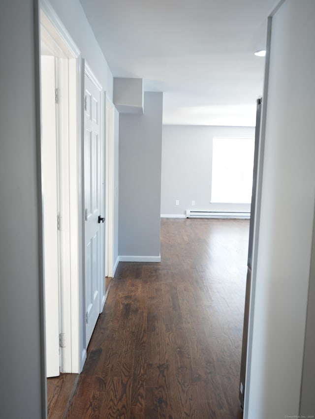 corridor featuring a baseboard heating unit and dark wood-type flooring