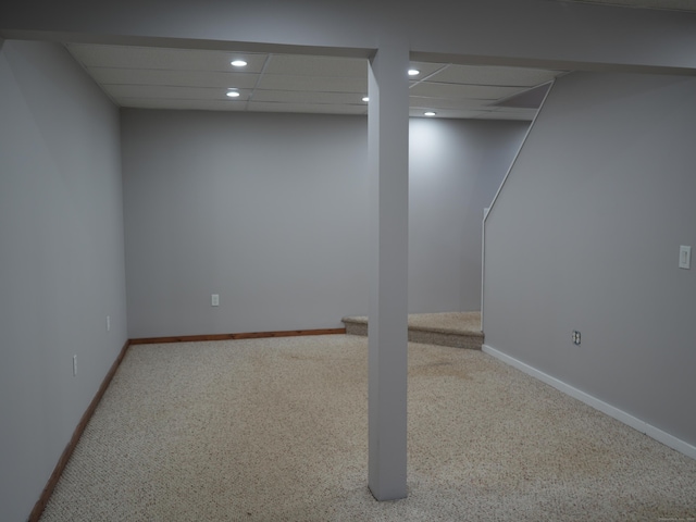 basement featuring a paneled ceiling and carpet floors