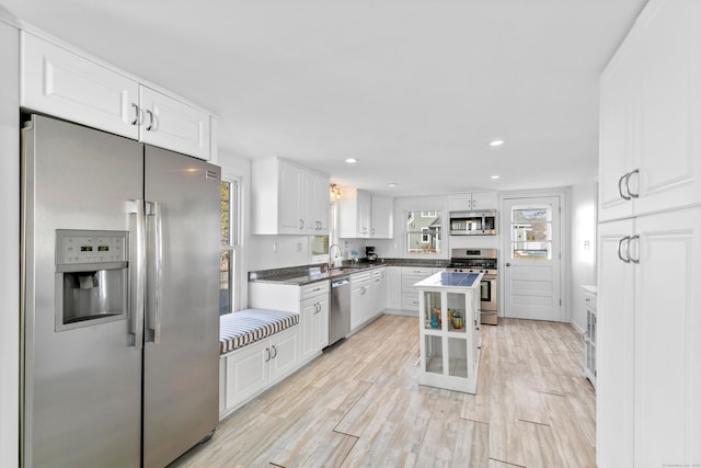 kitchen with a kitchen island, sink, light wood-type flooring, stainless steel appliances, and white cabinets