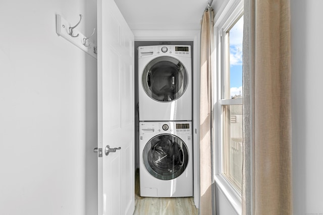 laundry area with stacked washer and clothes dryer and light wood-type flooring