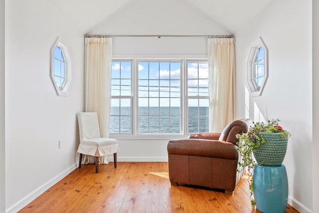 sitting room featuring a water view, hardwood / wood-style flooring, and lofted ceiling