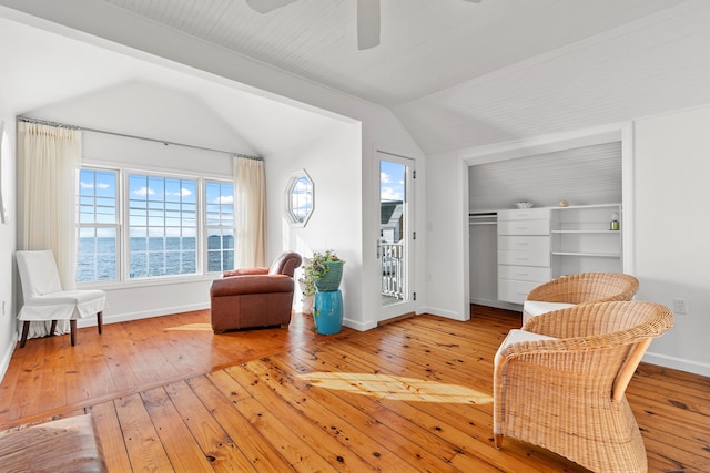 sitting room featuring ceiling fan, hardwood / wood-style floors, lofted ceiling, and a water view