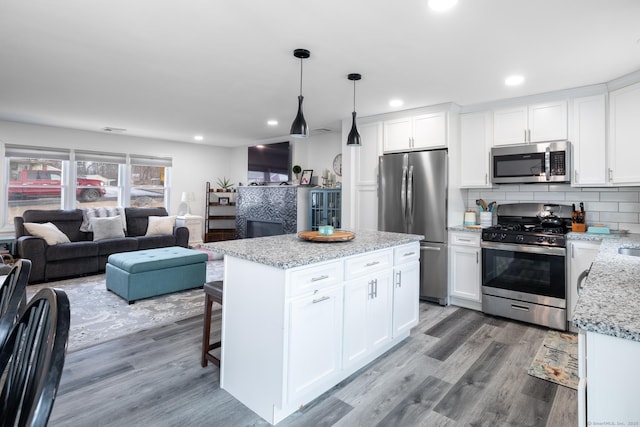 kitchen featuring white cabinets, a center island, stainless steel appliances, and pendant lighting