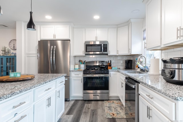 kitchen with pendant lighting, dark wood-type flooring, white cabinetry, stainless steel appliances, and backsplash