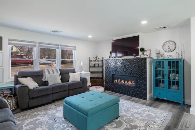 living room with a tile fireplace and hardwood / wood-style floors