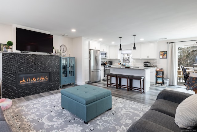 living room featuring a tiled fireplace and light hardwood / wood-style floors