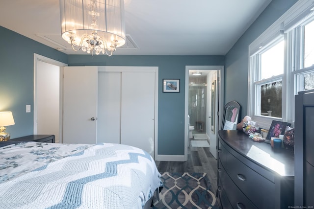 bedroom with dark hardwood / wood-style floors, a closet, ensuite bath, and a chandelier