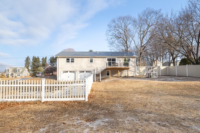 rear view of house featuring a garage and a wooden deck