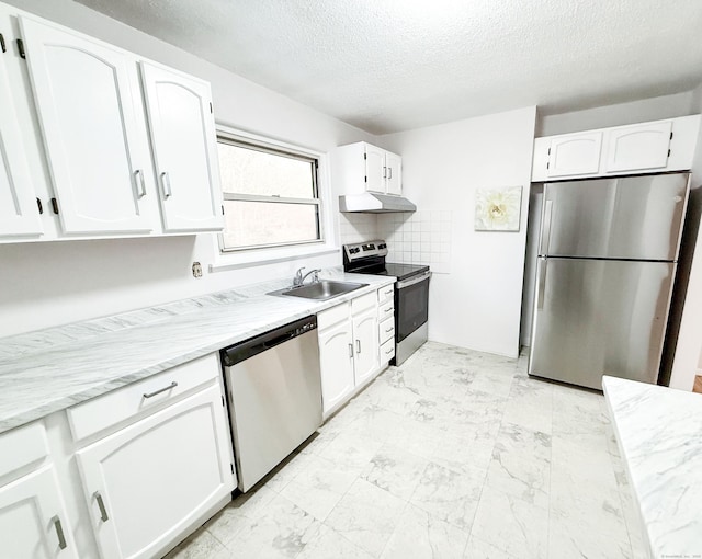 kitchen featuring light stone countertops, a textured ceiling, appliances with stainless steel finishes, white cabinetry, and sink