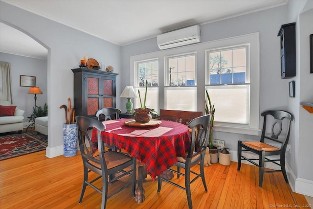 dining space with crown molding, an AC wall unit, a wealth of natural light, and light wood-type flooring