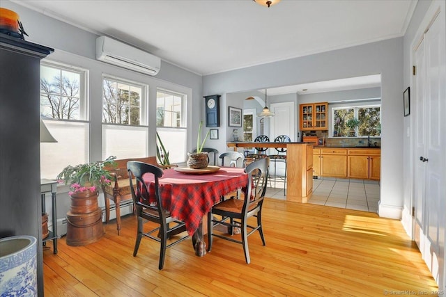 dining area featuring plenty of natural light, a wall mounted air conditioner, and light wood-type flooring