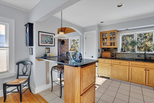 kitchen featuring sink, a breakfast bar area, a center island, ornamental molding, and light tile patterned flooring