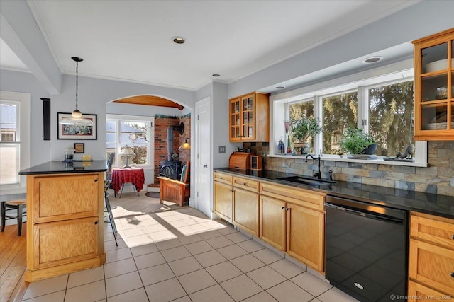 kitchen with pendant lighting, tasteful backsplash, dishwasher, sink, and a wood stove