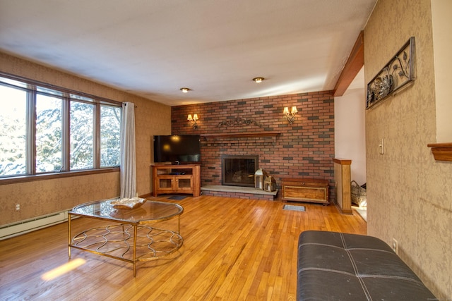 living room with baseboard heating, a fireplace, and light hardwood / wood-style flooring