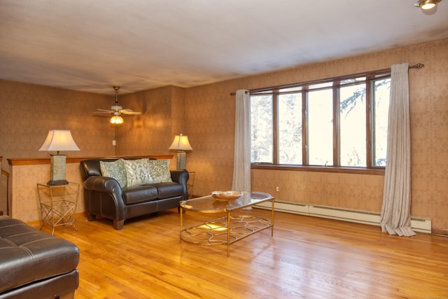 living room featuring ceiling fan, a baseboard heating unit, and light wood-type flooring