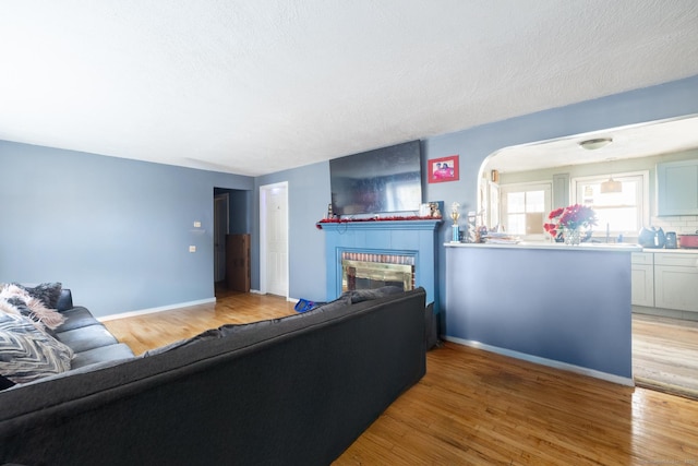 living room featuring a brick fireplace, a textured ceiling, and light wood-type flooring