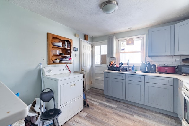 laundry room with washer / clothes dryer, sink, a textured ceiling, and light wood-type flooring