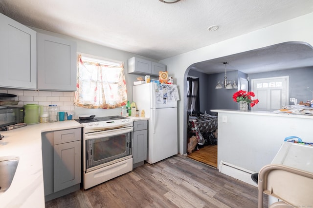 kitchen with hanging light fixtures, white appliances, gray cabinets, and decorative backsplash